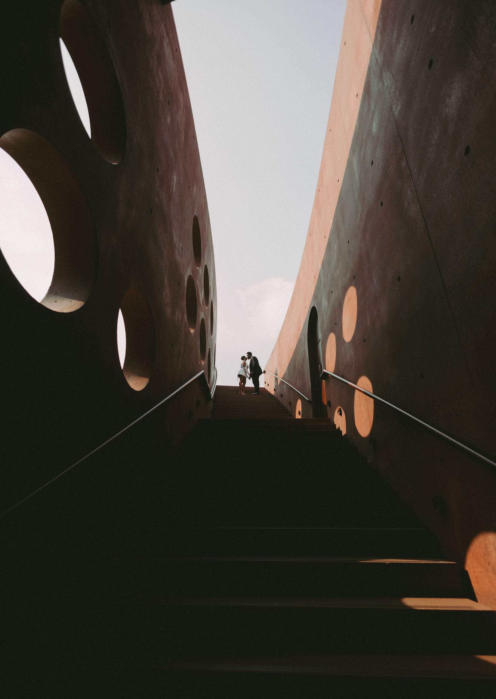 Couple kissing at the top of a staircase between sculpted walls